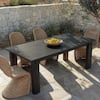 Dining table with wicker chairs set outdoors in a desert landscape.