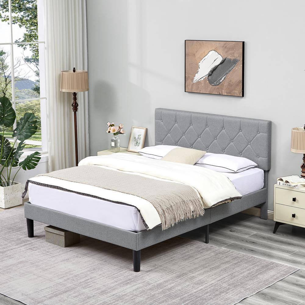 Gray upholstered platform bed with a tufted headboard in a bright room.
