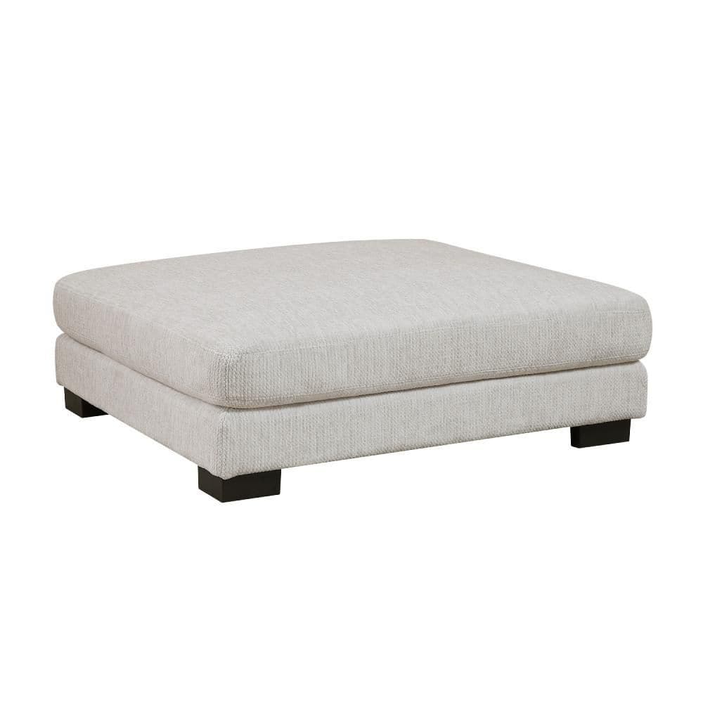 Square ottoman in beige fabric, viewed from above.