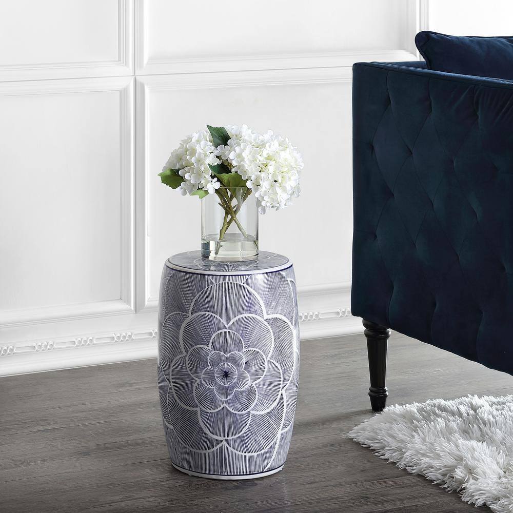 Ceramic drum garden stool next to a sofa with flowers on a dark floor.