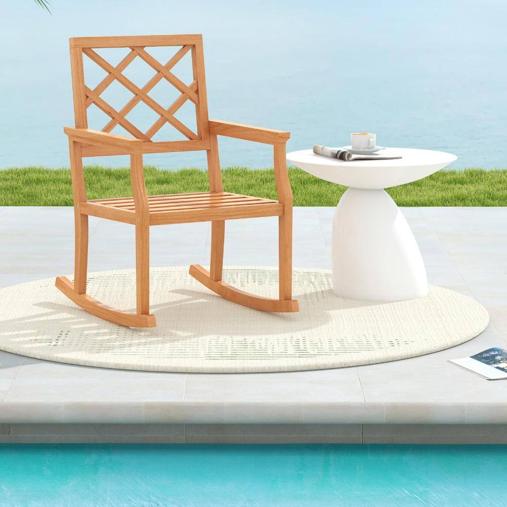 Teak wood rocking chair next to a white pedestal table by a pool.