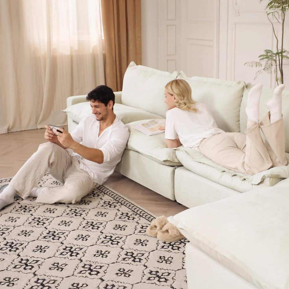 A man and woman relaxing on a beige linen modular sectional sofa.