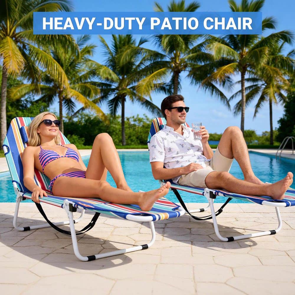 Two people sitting on colorful striped lounge chairs by a swimming pool.