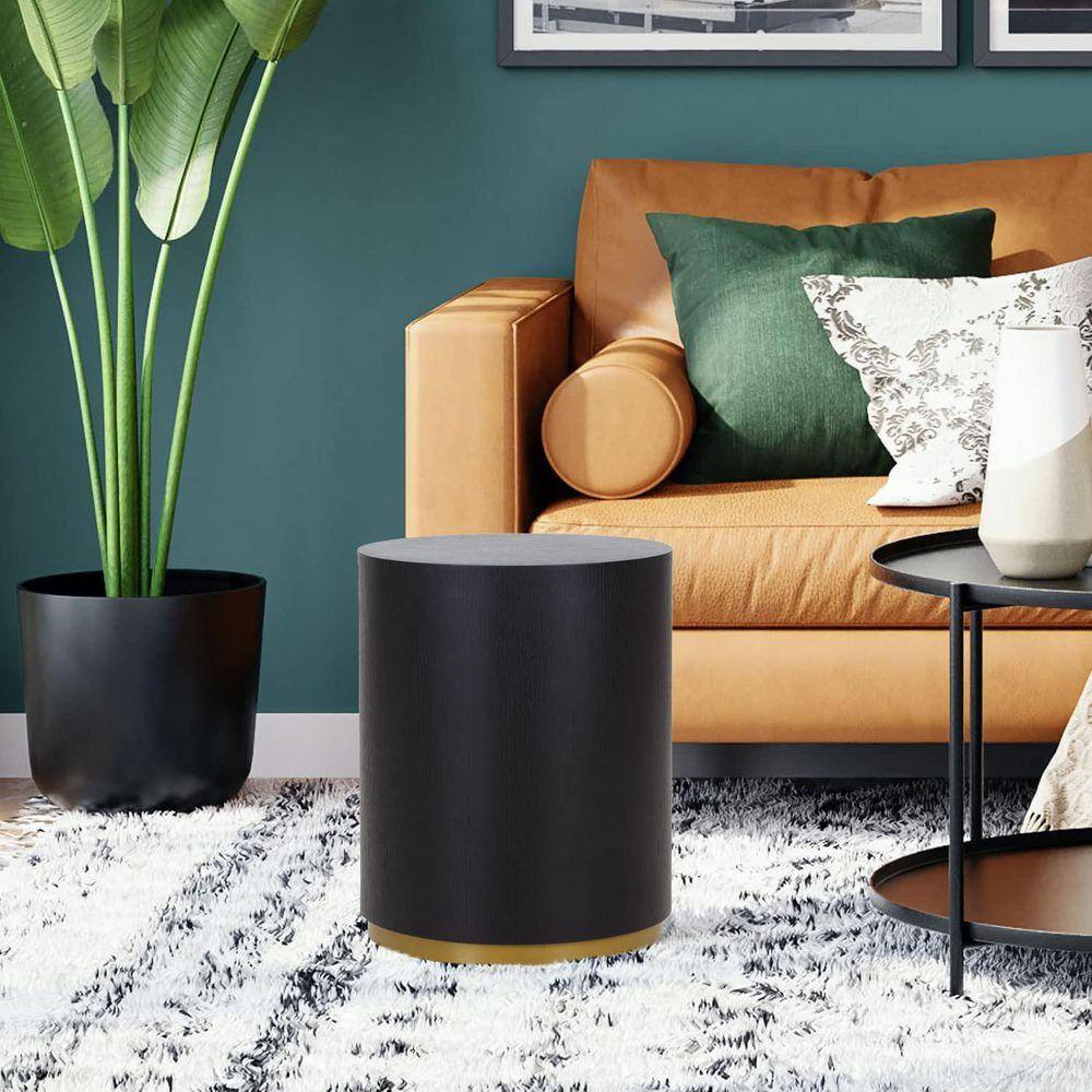 Black round coffee table next to a sofa and plant.