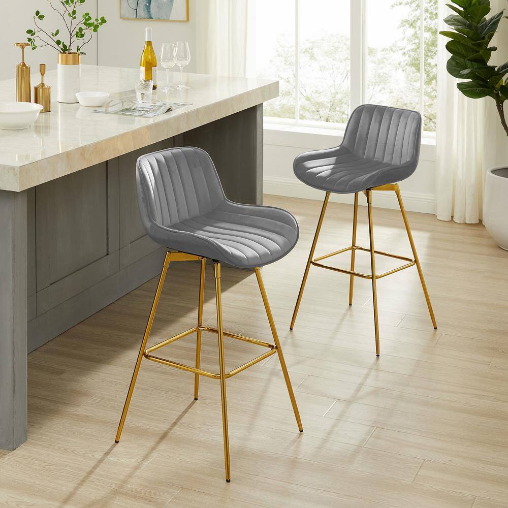 Two dark gray fabric swivel bar stools with gold metal legs in a bright room.