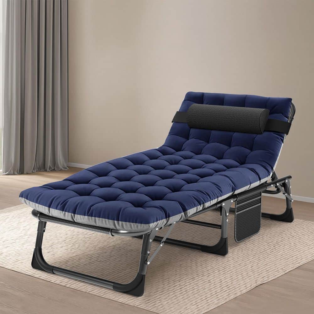 Navy blue tufted folding chaise lounge chair with black headrest pillow in an indoor setting.
