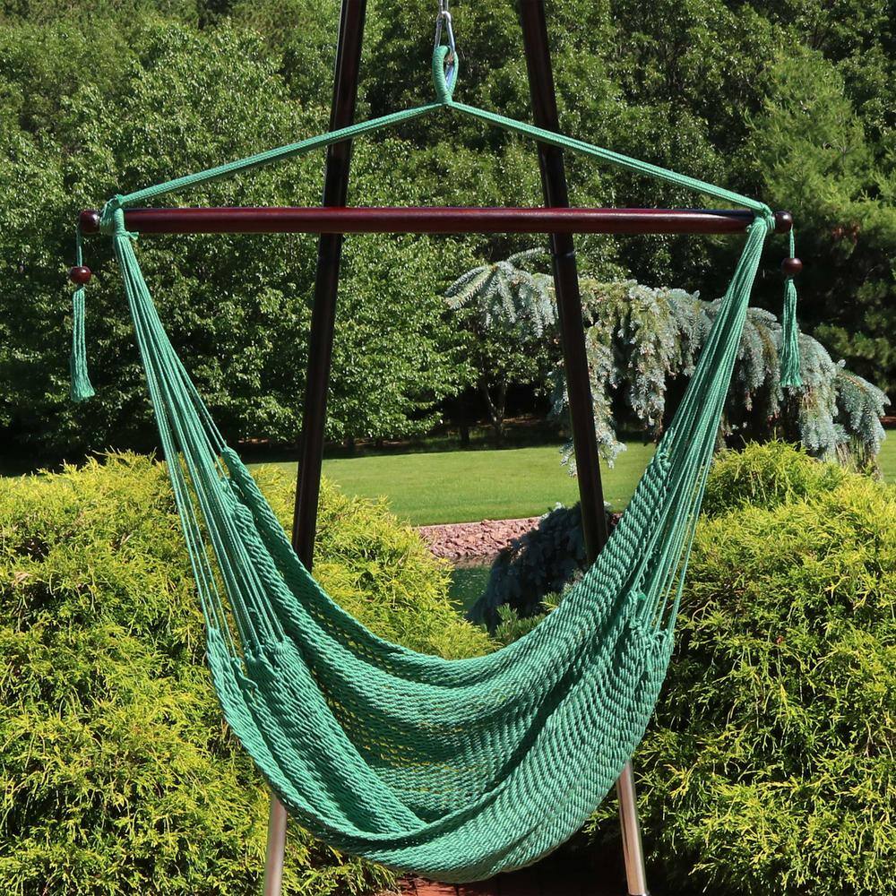 Green woven rope hammock chair hanging from a stand.