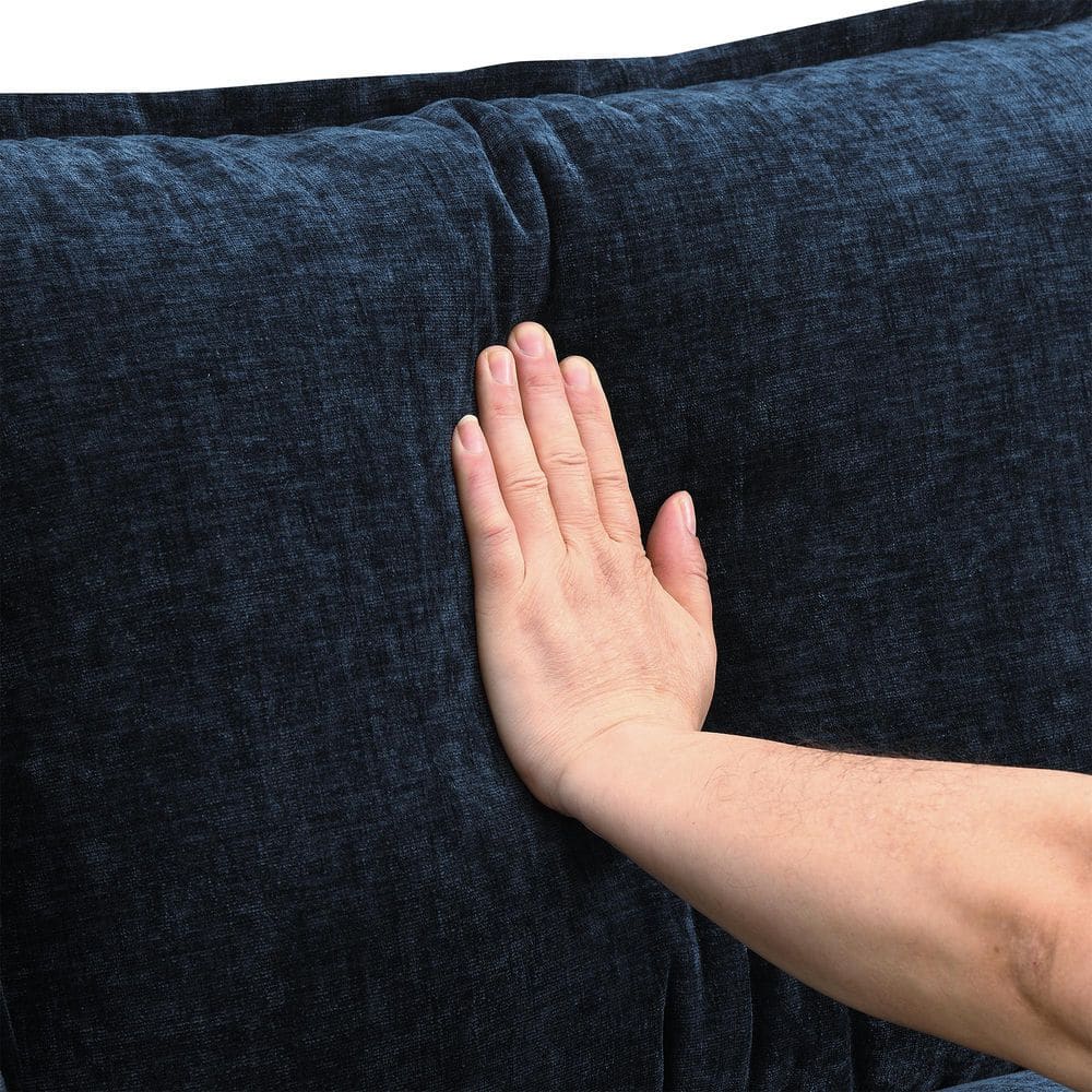 Hand touching the textured blue chenille fabric of the sofa.