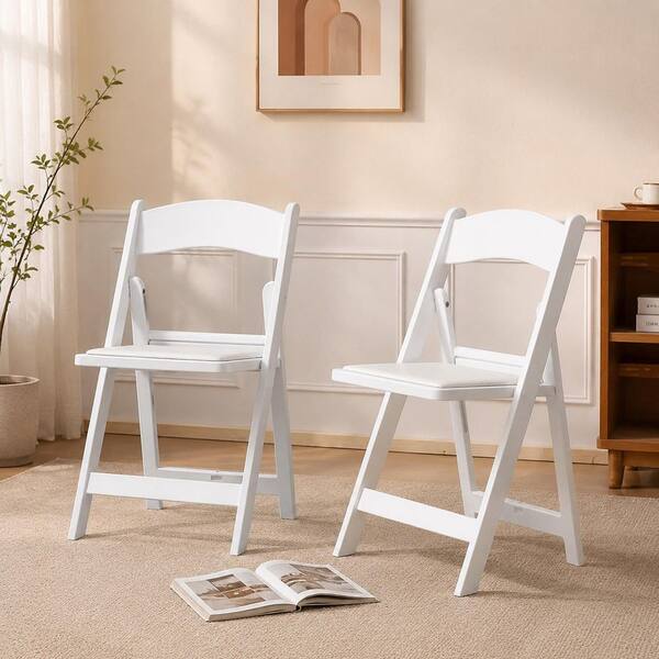 Two white folding chairs on a rug in a bright room.