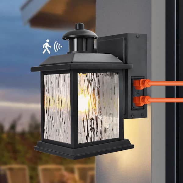 Cedar Hill 11 in. Black Motion Sensor Dusk to Dawn Outdoor Wall Sconce with Outlet 1-Light Water Rippled Glass Shade Lamp