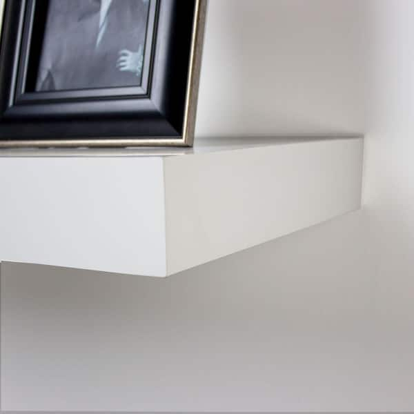 White floating shelves are mounted beside glass front cabinets positioned  over a white and gray…