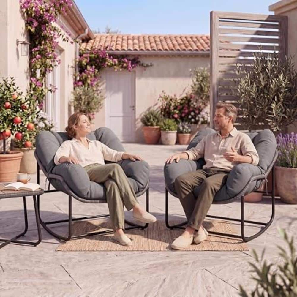 Two people relaxing in gray papasan rocking chairs on an outdoor patio.