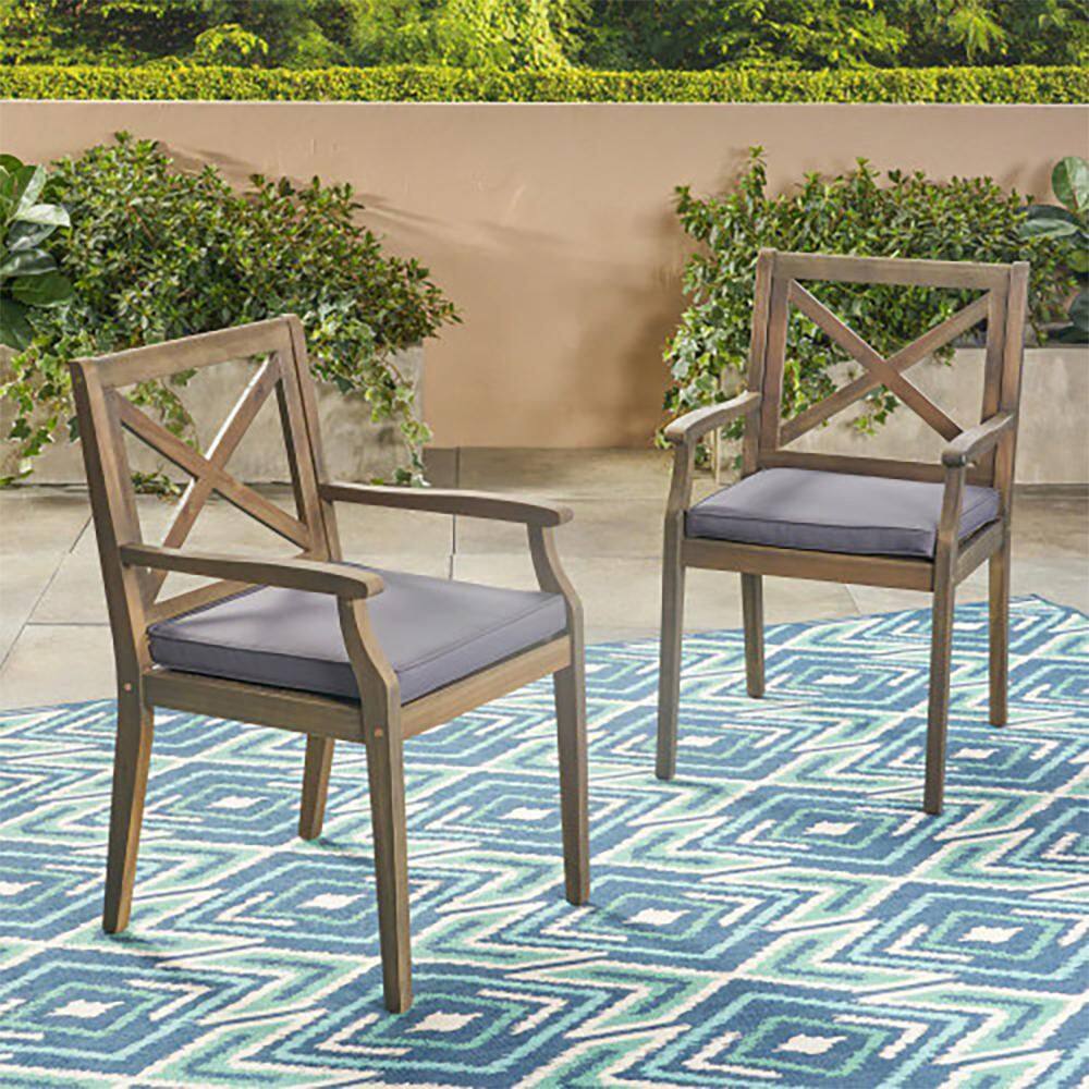 Two grey outdoor dining chairs on a blue patterned rug.