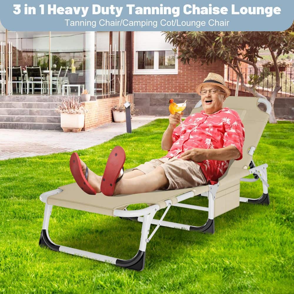 A man in a red shirt relaxing on a beige folding tanning chair on a lawn.