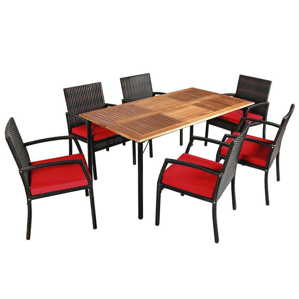 7-piece outdoor dining set with a rectangular acacia wood table and six brown wicker chairs with red cushions.