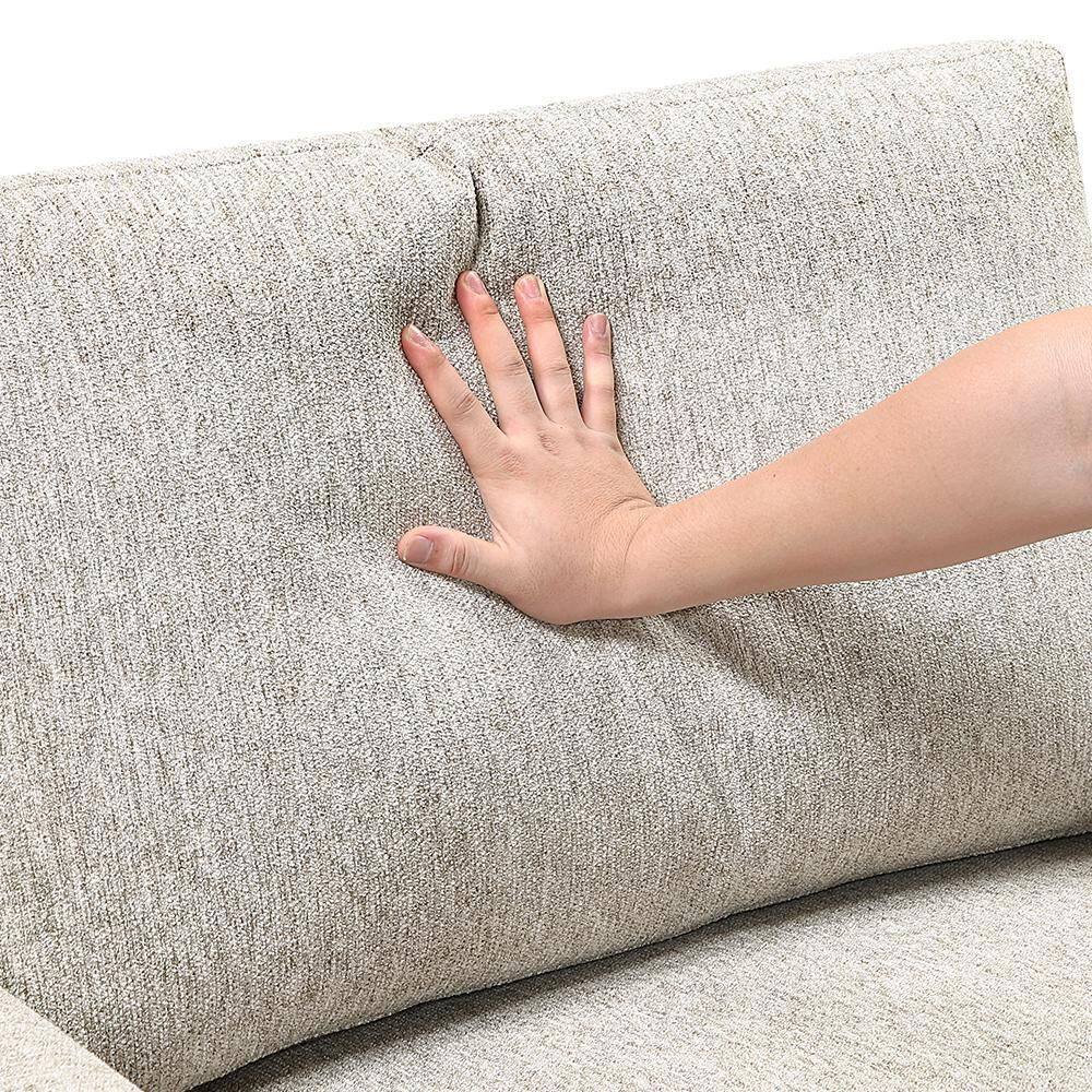 Close-up of a hand pressing into the sand-colored microfiber upholstery of a sofa.
