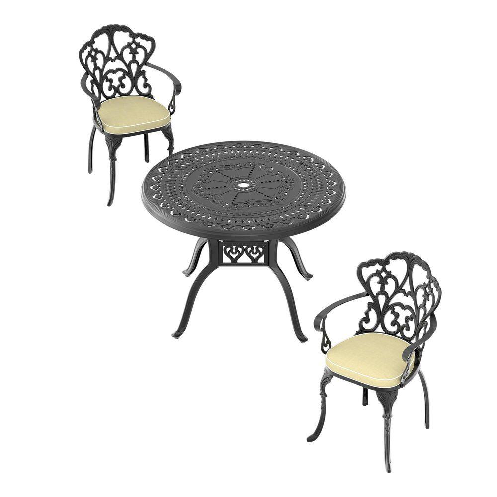 Black 3-piece cast aluminum outdoor dining set with beige cushions on a white background.