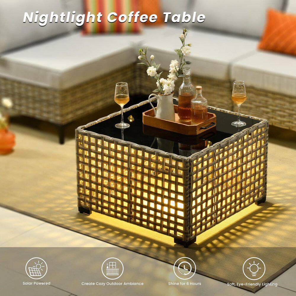 Close-up of the lighted wicker coffee table with a glass top and decorative items.