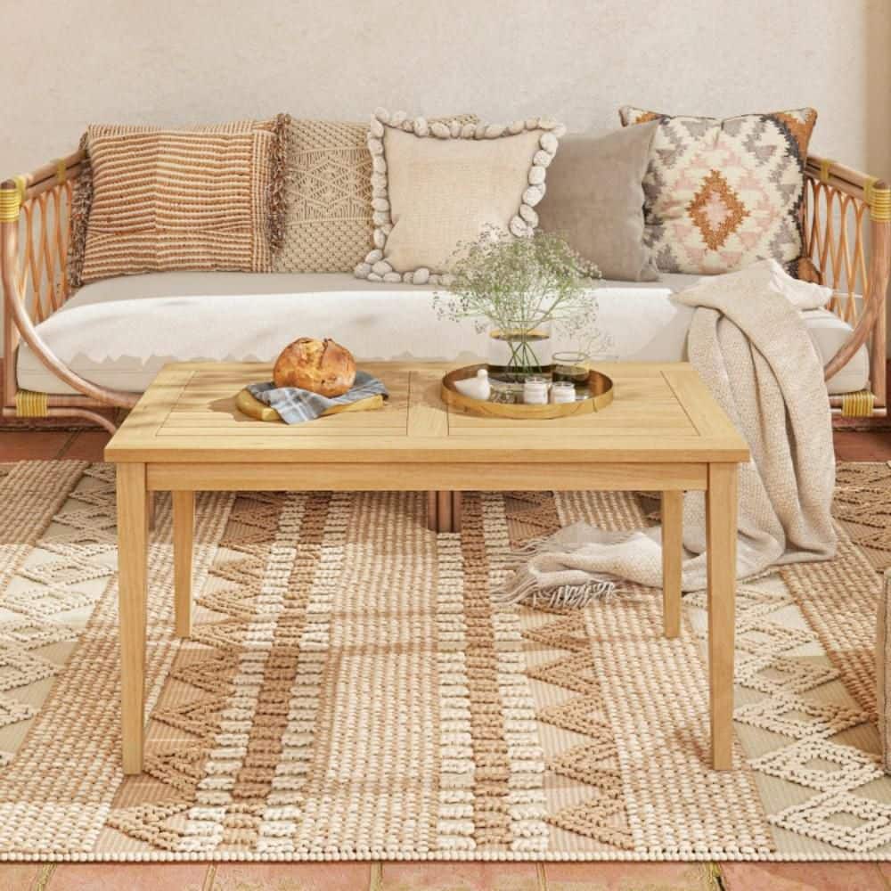 Teak wood coffee table in a bright, airy room with a sofa.