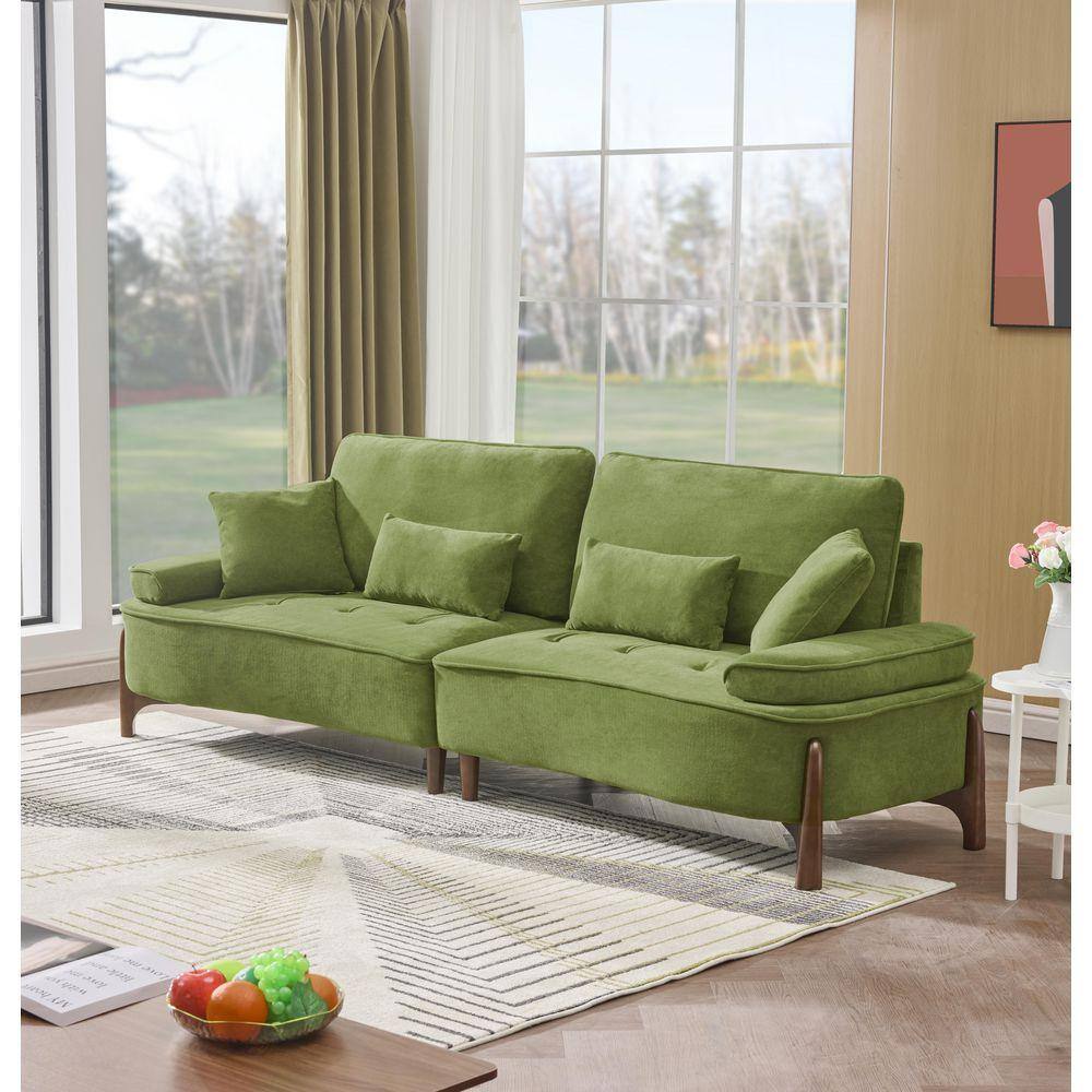 Green velvet futon sofa in a bright room with a window.