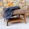 Outdoor ottoman with a dark protective cover on top.