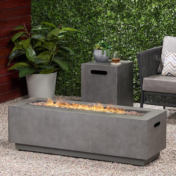 a rectangular fire pit with hidden propane tank storage surrounded by outdoor furniture in with plant wall in the background