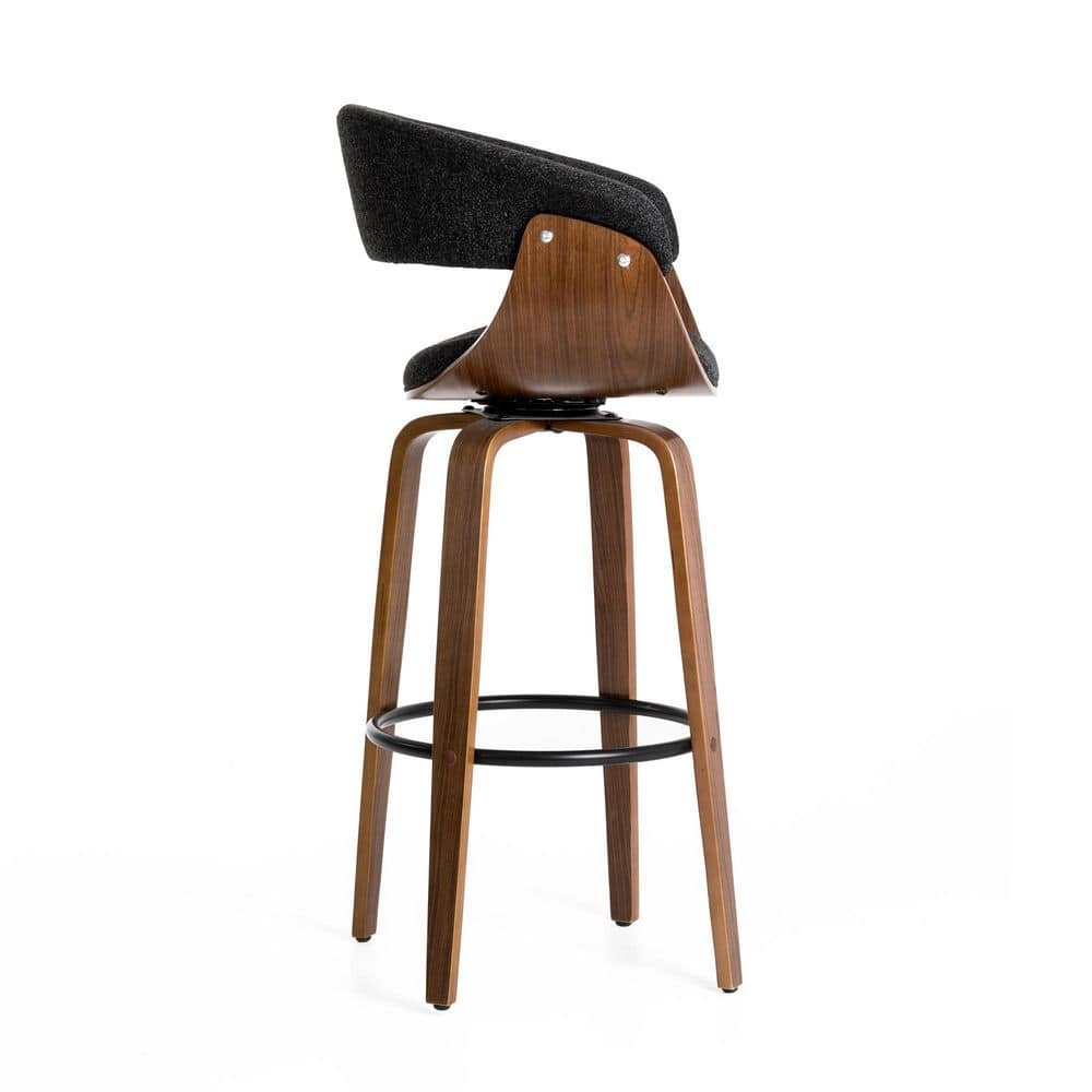 Rear view of a modern black fabric swivel bar stool with walnut frame.