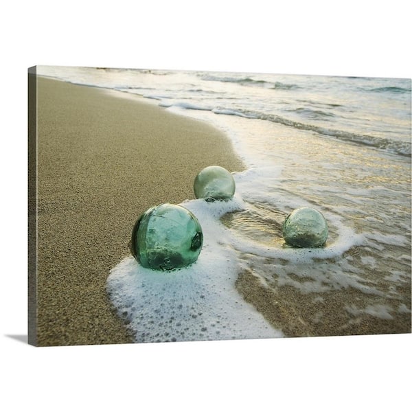 GreatBigCanvas "Three Glass Fishing Floats Roll On The Sandy Shoreline With Ripples..." by Mary Van de Ven Canvas Wall Art