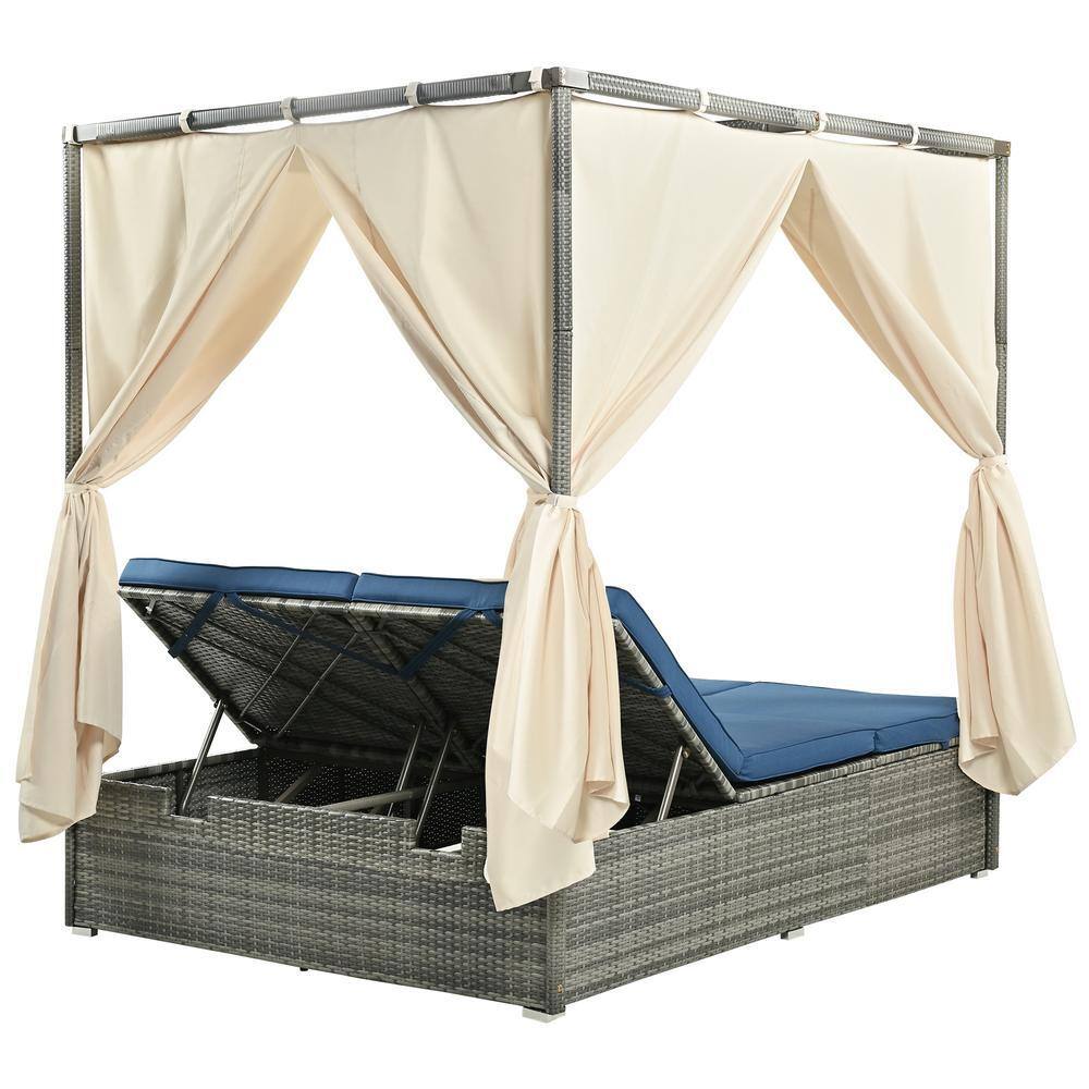 Gray wicker daybed partially open with blue cushions and tan curtains.