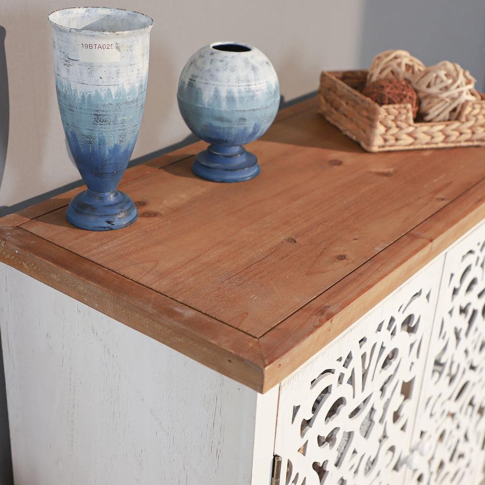 Close-up of the natural wood top and hollow-carved door of the white accent cabinet.