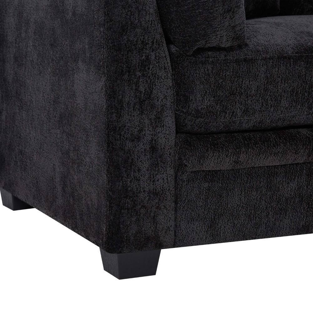 Close-up view of the corner and arm of a black chenille sofa.
