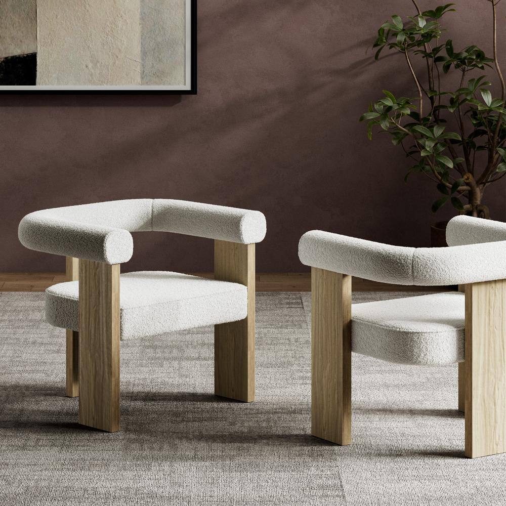 Two cream bouclé accent chairs in a room setting.