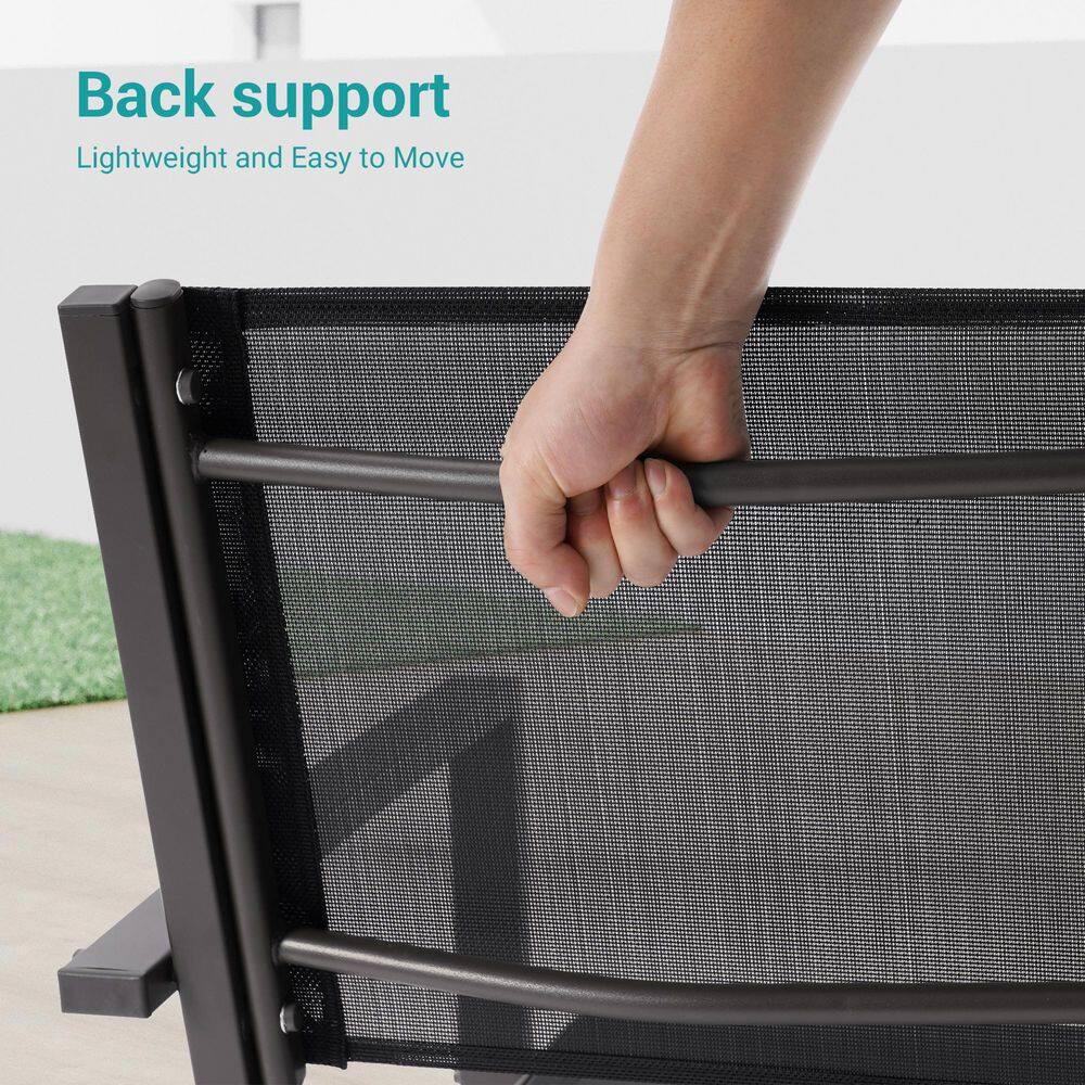 A hand gripping the top rail of a brown frame patio chair to move it.