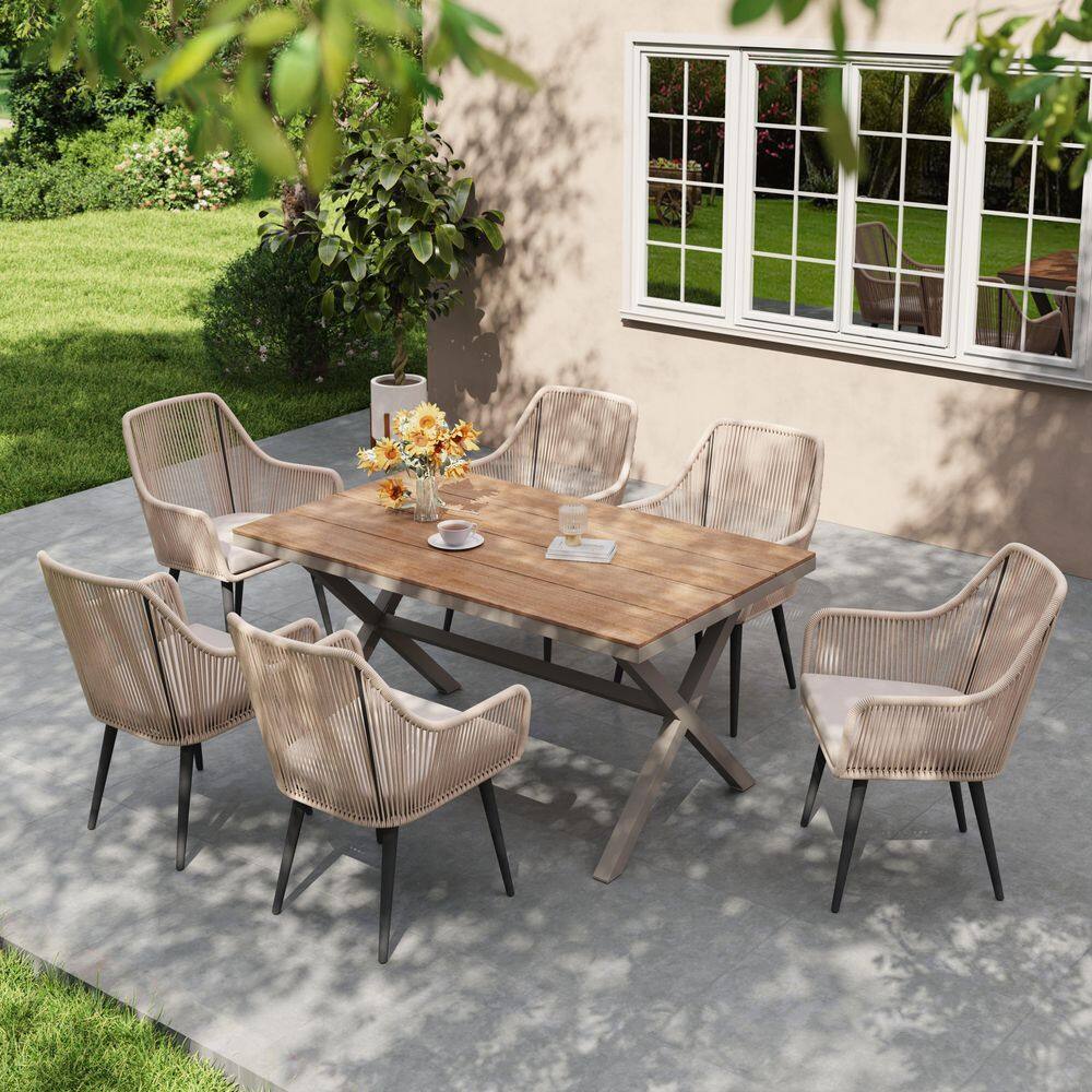 Outdoor wood patio dining set with rattan chairs and greenery.