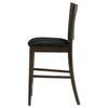 Side view of an espresso wood counter stool with black vinyl upholstery.