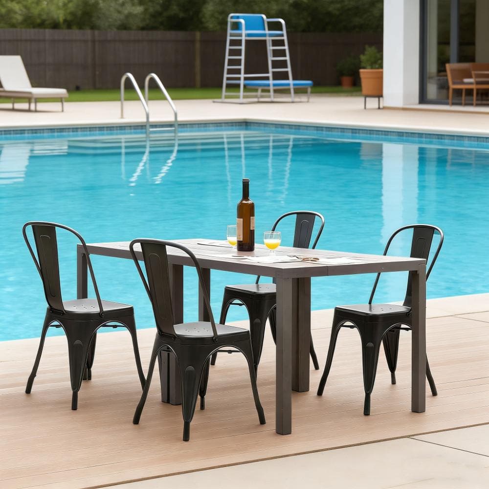 Four black metal dining chairs around a rectangular table by a swimming pool.