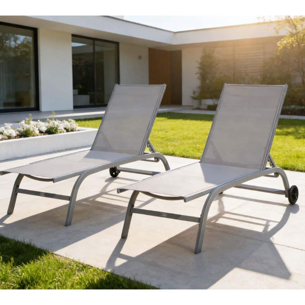 Two grey outdoor chaise lounges on a paved outdoor area.