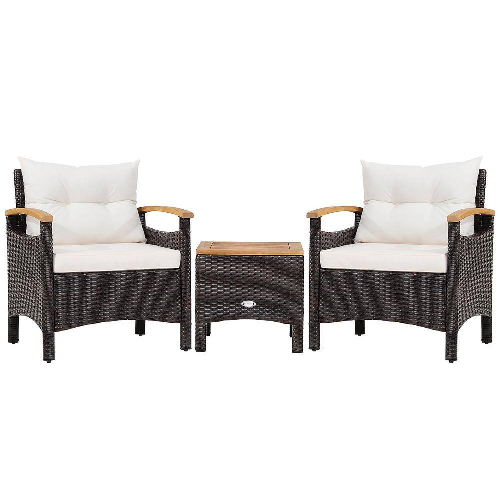 Three-piece patio rattan furniture set featuring two armchairs and one side table with white cushions.