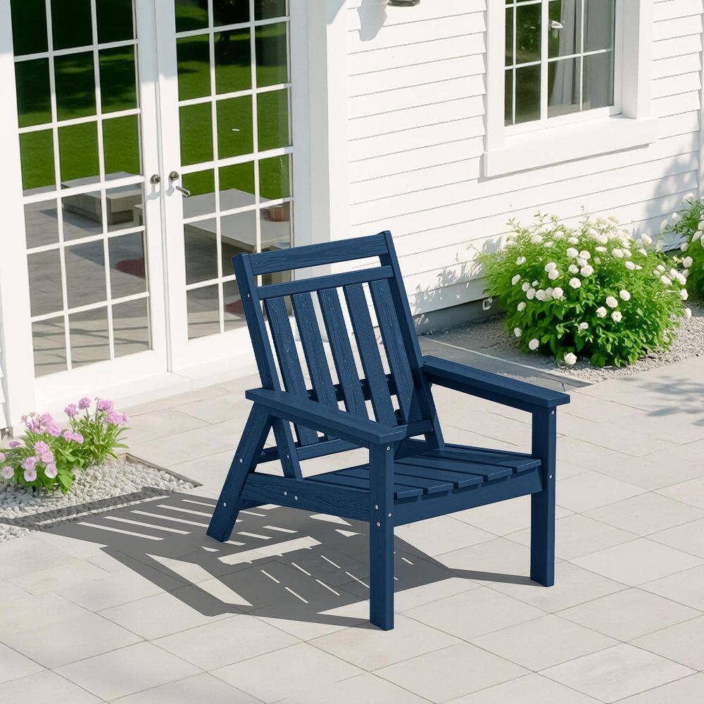 Dark blue Adirondack chair on a white patio next to white flowers.