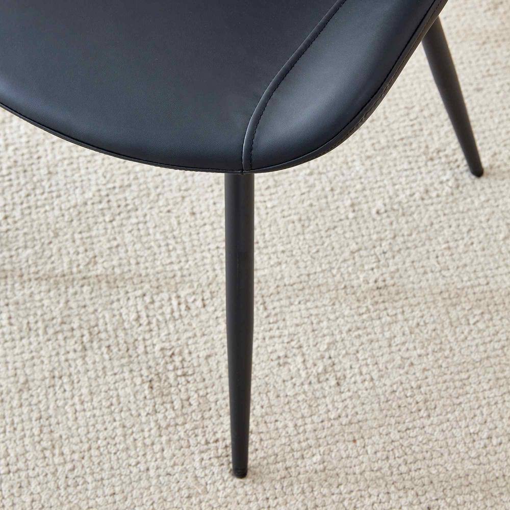 Close-up of a black dining chair seat and its slim metal leg.