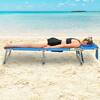 Person relaxing on a blue folding chaise lounge on the sand.