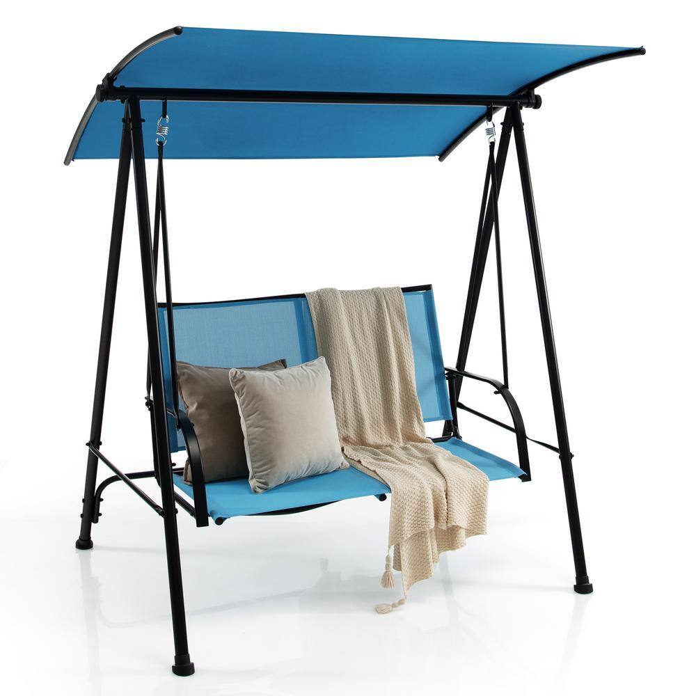Patio swing set in a backyard with cushions and a throw blanket.