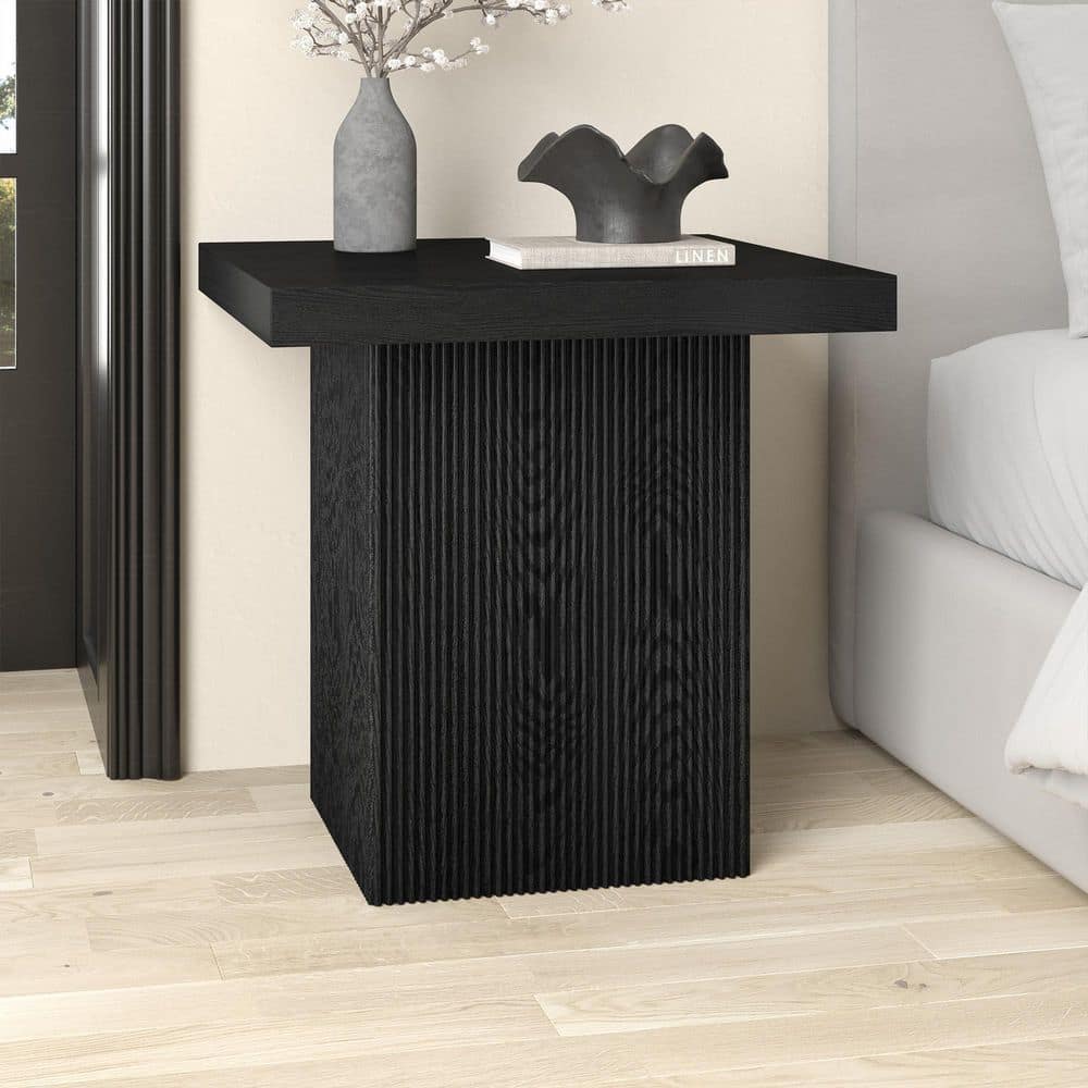 Black square fluted end table with decor on top.