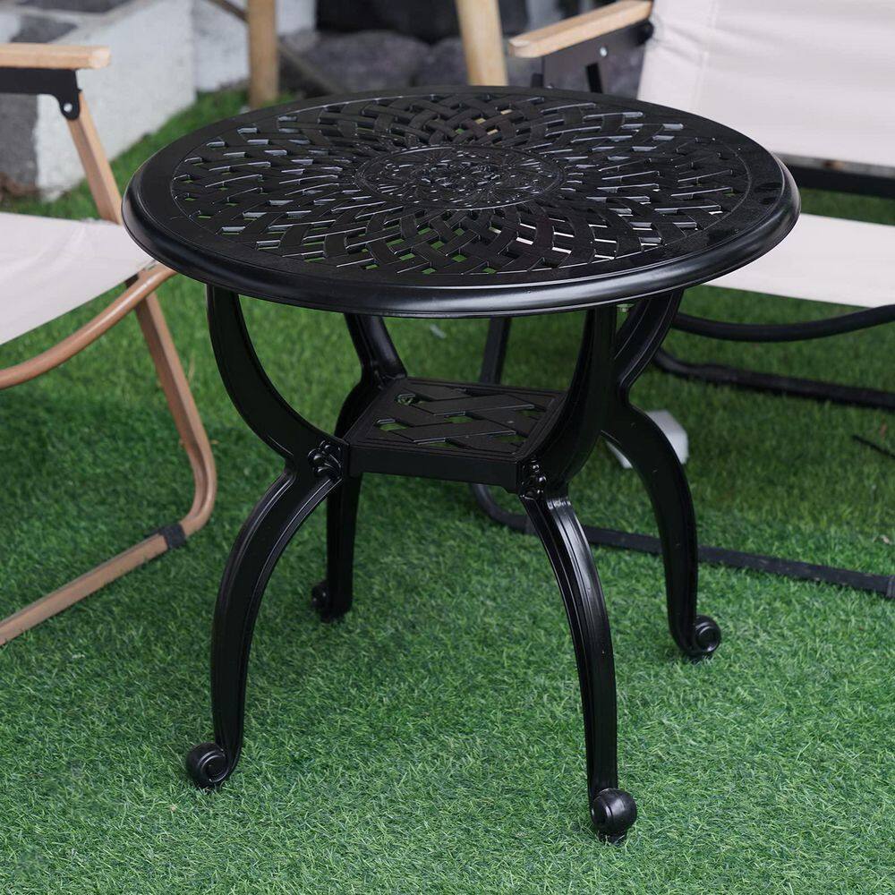 Black cast aluminum round side table on artificial grass.