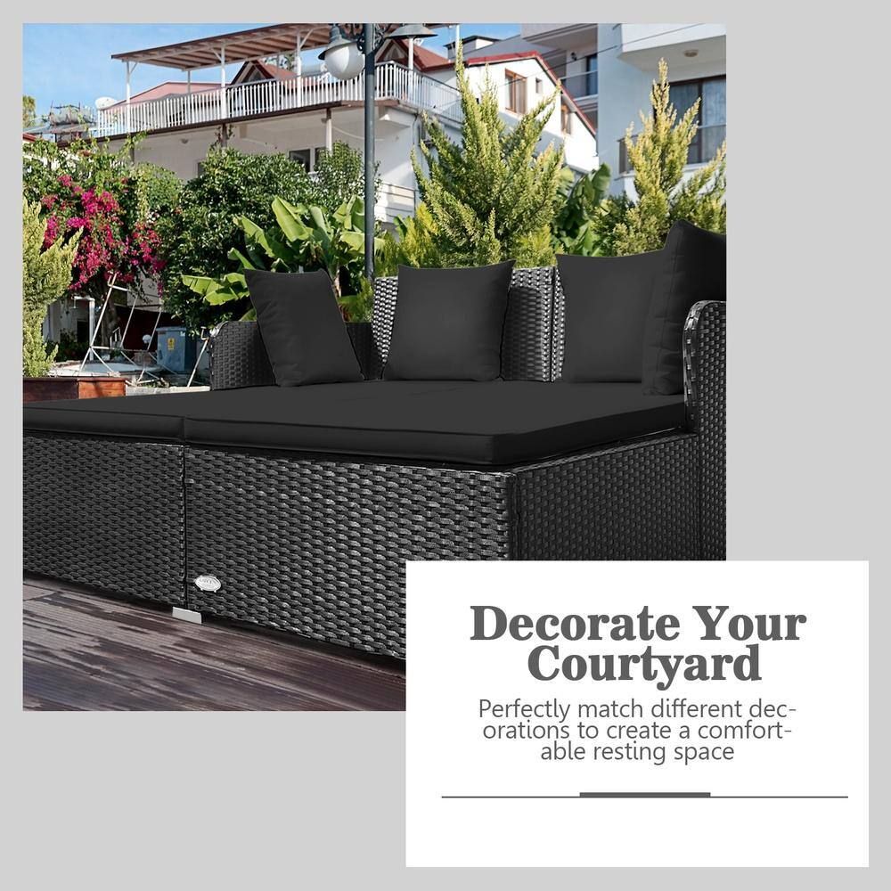 Close-up of a black rattan outdoor daybed in a courtyard setting.