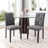Two gray upholstered dining chairs placed at a round marble-top table.
