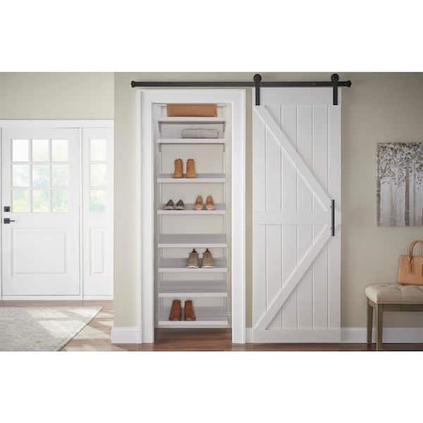 Large white walk-in closet features floor-to-ceiling custom shoe shelves  and a light tan bench.
