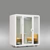 White office sound pod booth with two yellow chairs inside.