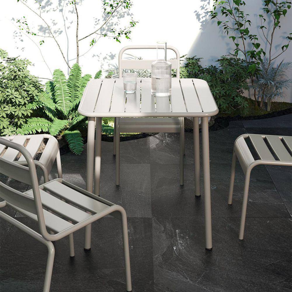 White square metal outdoor dining table with matching chairs in a courtyard.