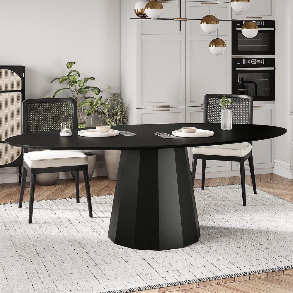 Black oval pedestal dining table paired with two black and white chairs.